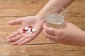 A womans hand holding a variety of small red and white pills and a glass of water Royalty Free Stock Photo